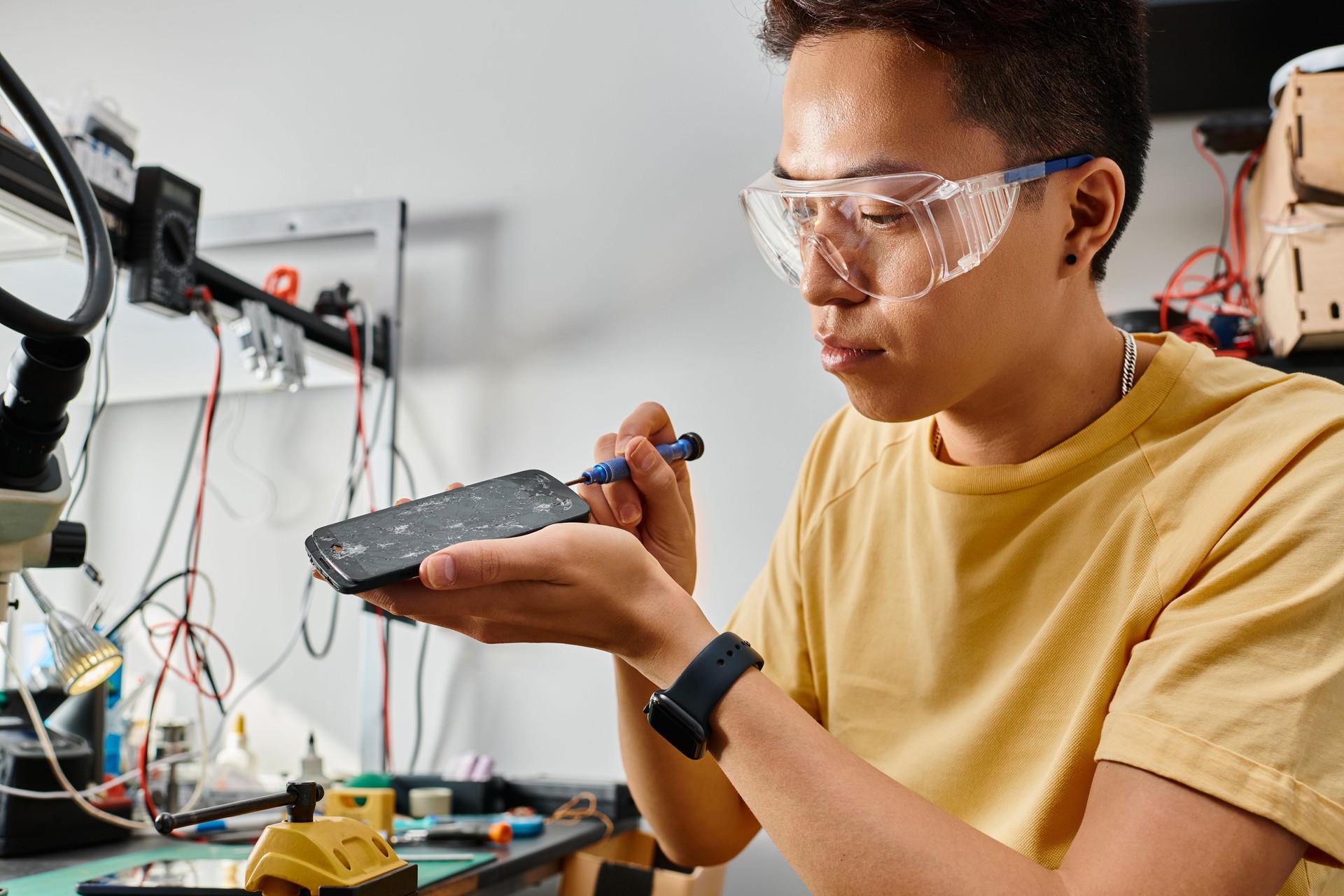 Handsome man performing phone repair work at a service center during daytime