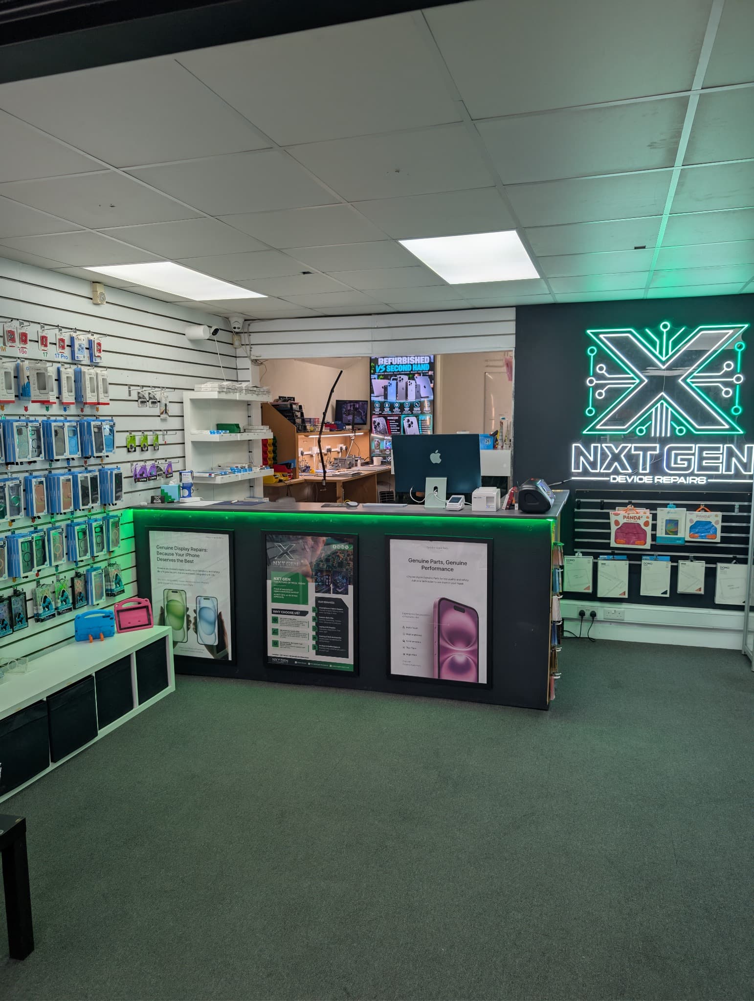 Device repair shop interior with a neon sign, green-lit counter, and phone accessory displays.